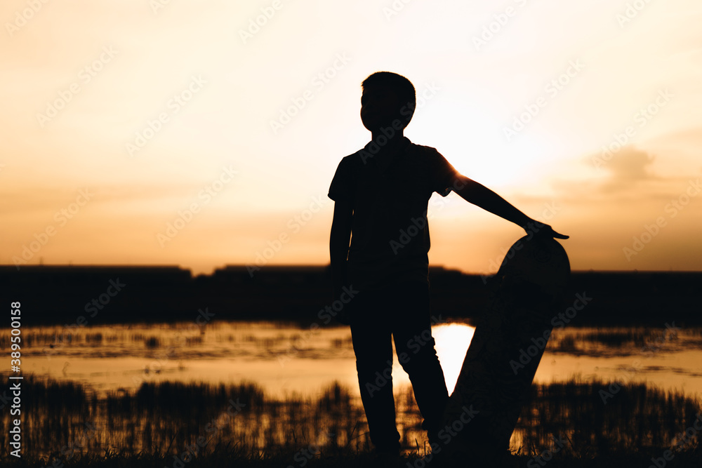 silhouette boy with a skateboard at sunset 