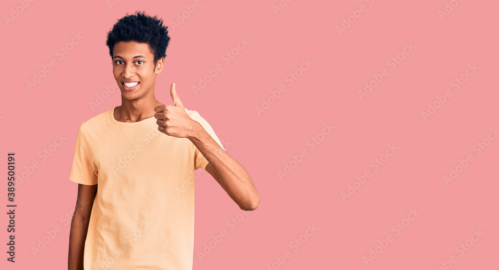 Young african american man wearing casual clothes doing happy thumbs up gesture with hand. approving expression looking at the camera showing success. Young african american man wearing casual clothes doing happy thumbs up gesture with hand. approving expression looking at the camera showing success.