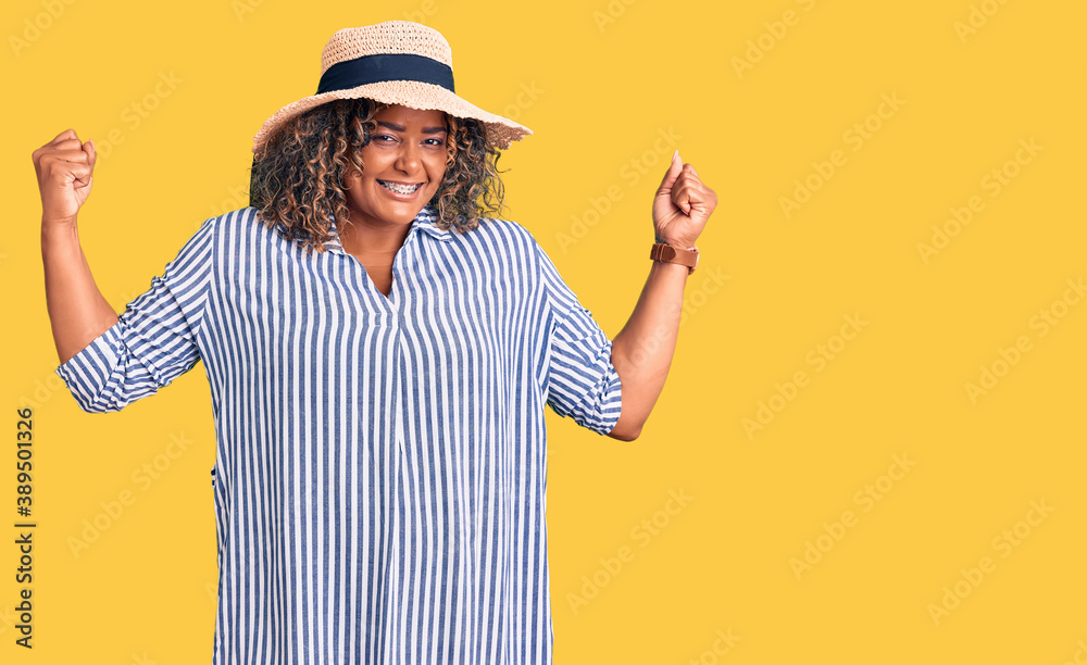 Young african american plus size woman wearing summer hat showing arms muscles smiling proud. fitness concept. Young african american plus size woman wearing summer hat showing arms muscles smiling proud. fitness concept.