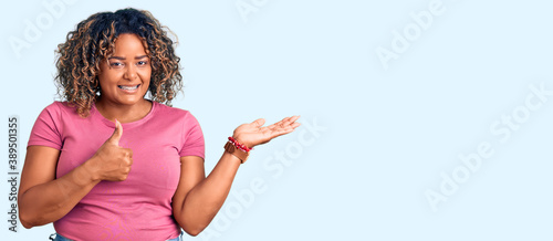 Young african american plus size woman wearing casual clothes showing palm hand and doing ok gesture with thumbs up, smiling happy and cheerful