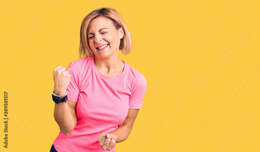 Young blonde woman wearing sportswear celebrating surprised and amazed for success with arms raised and eyes closed. winner concept. Young blonde woman wearing sportswear celebrating surprised and amazed for success with arms raised and eyes closed. winner concept.