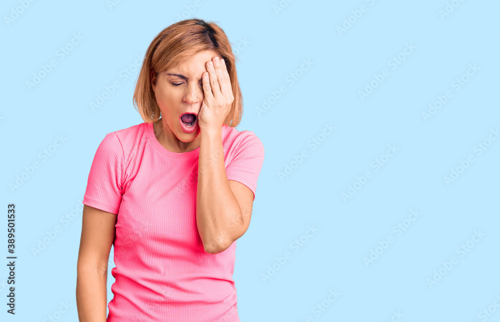 Fototapeta premium Young blonde woman wearing sportswear yawning tired covering half face, eye and mouth with hand. face hurts in pain.