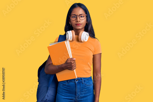 Obraz na plátně Young indian girl holding student backpack and books thinking attitude and sober