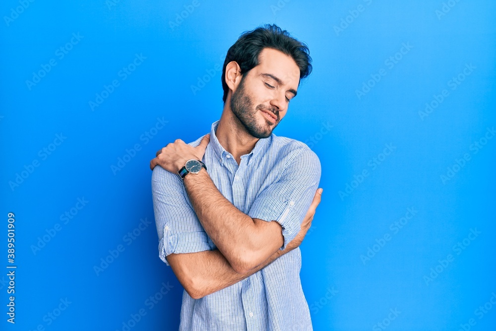 Young hispanic man wearing elegant summer shirt hugging oneself happy and positive, smiling confident. self love and self care Young hispanic man wearing elegant summer shirt hugging oneself happy and positive, smiling confident. self love and self care