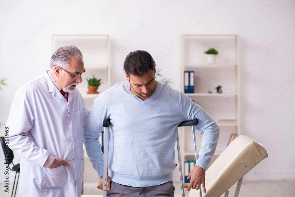 Fototapeta premium Young leg injured man visiting old doctor osteopath