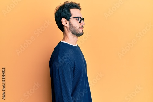 Young hispanic man wearing casual clothes and glasses looking to side, relax profile pose with natural face with confident smile.