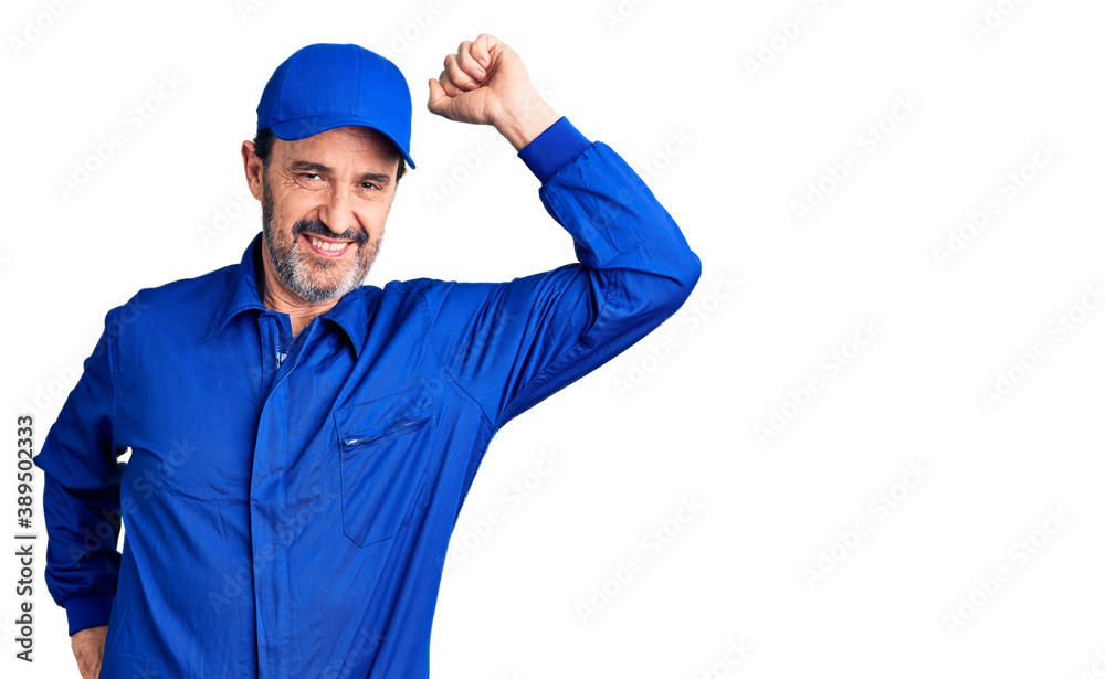 Middle age handsome man wearing mechanic uniform smiling confident touching hair with hand up gesture, posing attractive and fashionable Middle age handsome man wearing mechanic uniform smiling confident touching hair with hand up gesture, posing attractive and fashionable