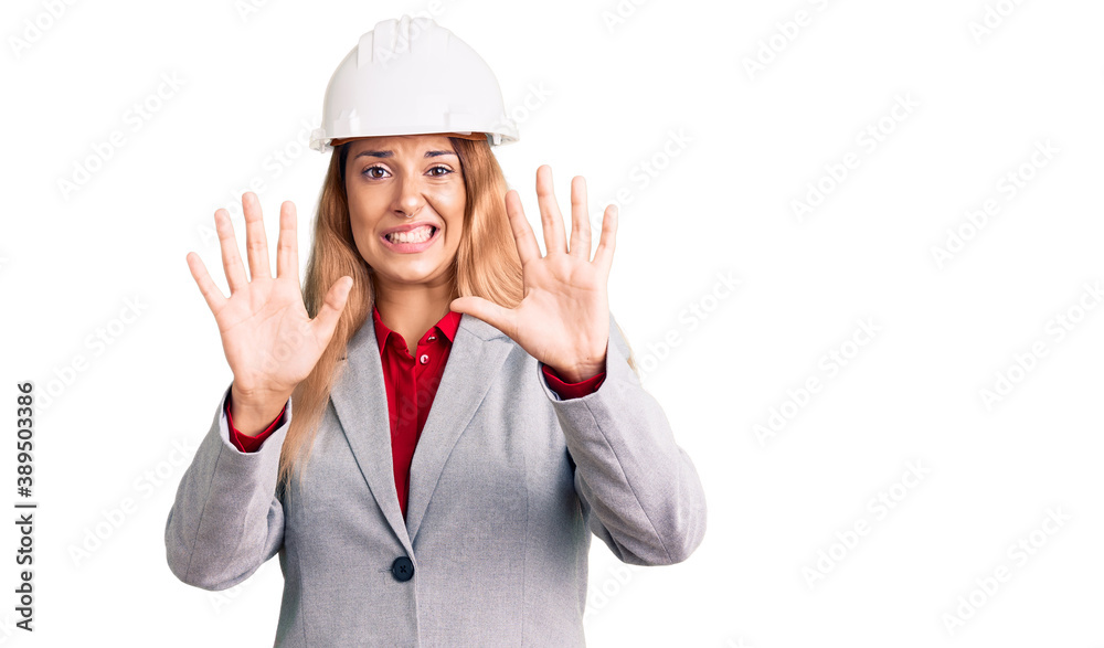 Beautiful young woman wearing architect hardhat afraid and terrified with fear expression stop gesture with hands, shouting in shock. panic concept. Beautiful young woman wearing architect hardhat afraid and terrified with fear expression stop gesture with hands, shouting in shock. panic concept.