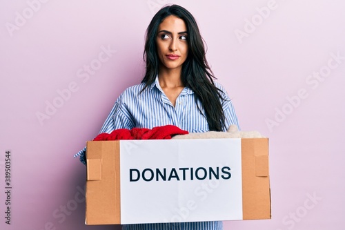 Beautiful hispanic woman volunteer holding donations box smiling looking to the side and staring away thinking. © Krakenimages.com