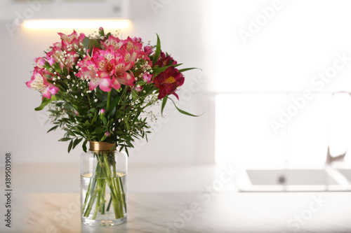 Vase with beautiful alstroemeria flowers on table in kitchen, space for text. Interior design