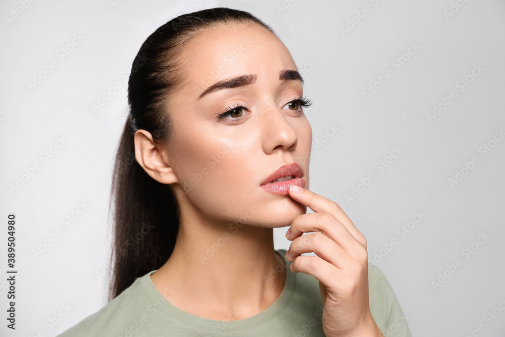 Woman with herpes touching lips on light grey background Woman with herpes touching lips on light grey background