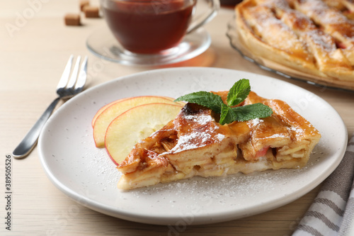 Slice of traditional apple pie served on wooden table, closeup