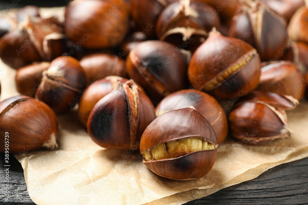 Tasty roasted edible chestnuts on black wooden table, closeup Tasty roasted edible chestnuts on black wooden table, closeup