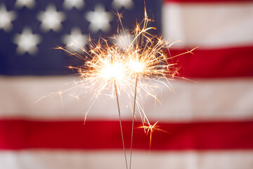 Bright burning sparklers against American flag, closeup