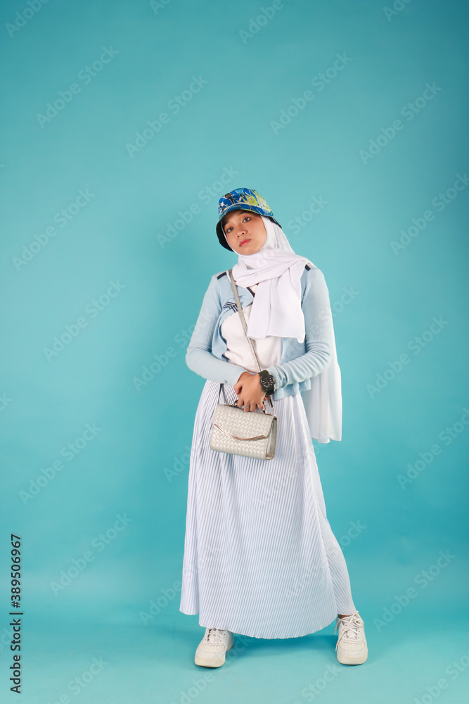 Fashion photo of a beautiful elegant young asian woman holding handbag posing over blue background. Fashion photo of a beautiful elegant young asian woman holding handbag posing over blue background.