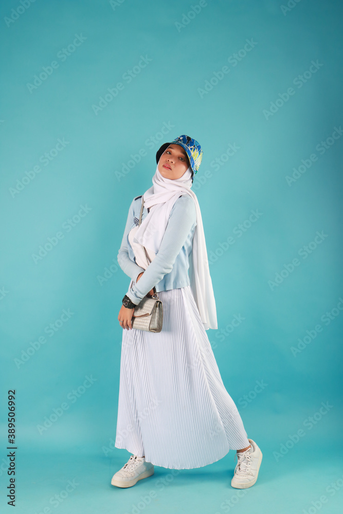 Fashion photo of a beautiful elegant young asian woman holding handbag posing over blue background. Fashion photo of a beautiful elegant young asian woman holding handbag posing over blue background.