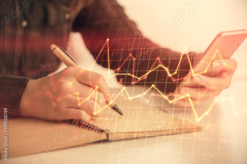 Double exposure of forex graph sketch hologram and woman holding and using a mobile device. Stock market concept.