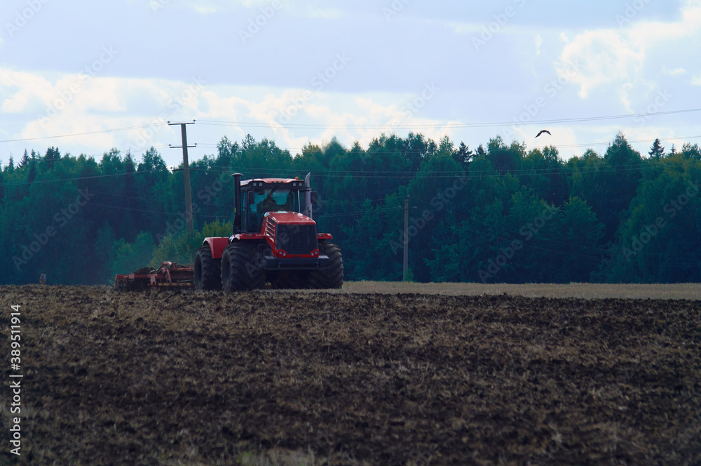 Red tractor plowing a green agricultural field Red tractor plowing a green agricultural field