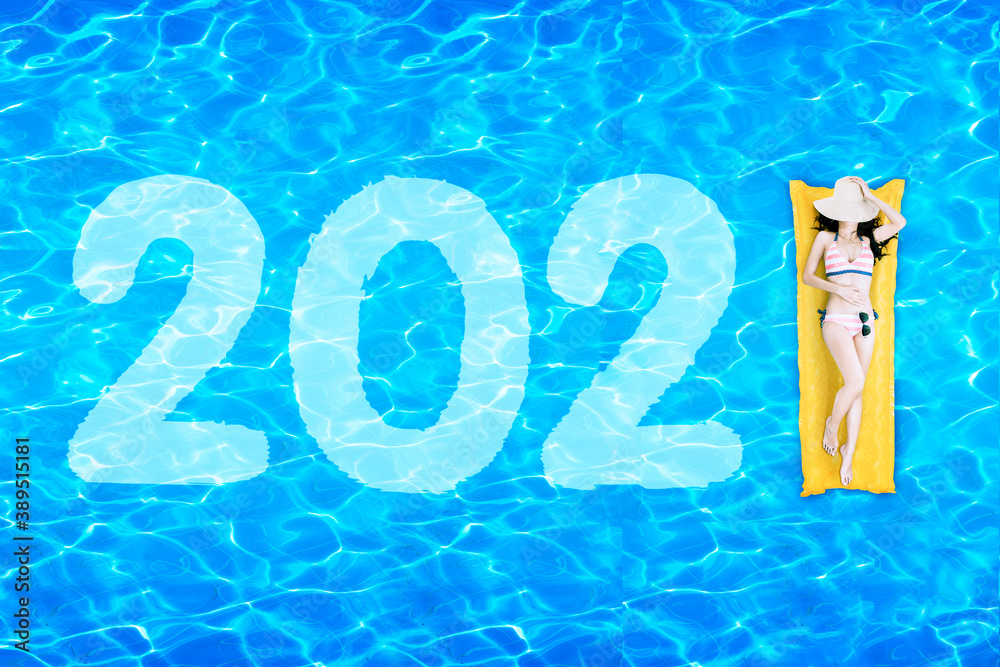 Woman lying on inflatable float with number 2021 - obrazy, fototapety, plakaty 