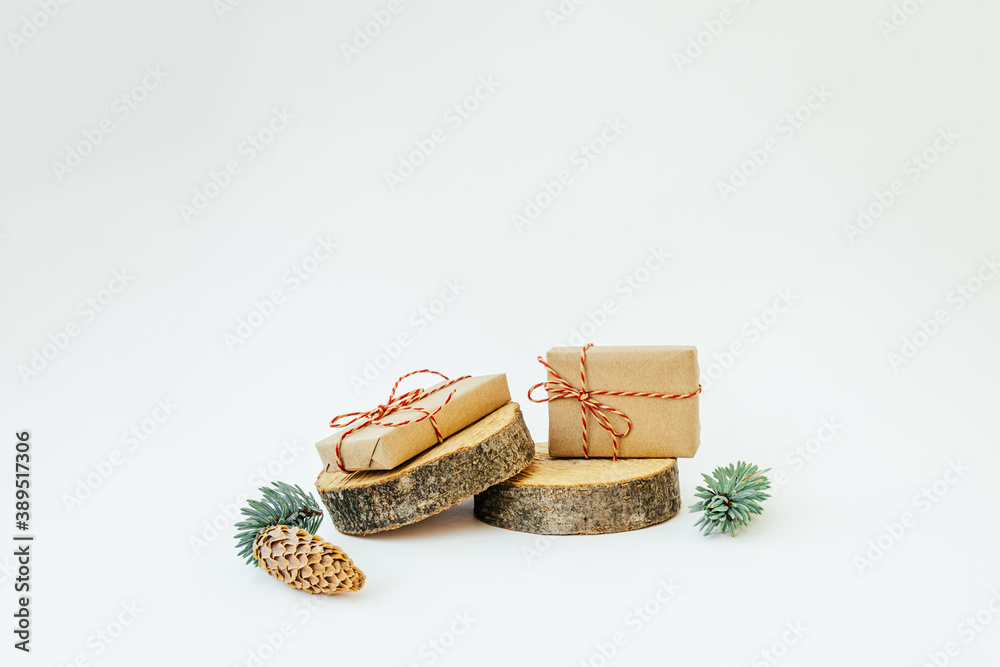 Two craft gifts on the wooden round cylinders shapes on the light background. Concept Christmas and New Year. Copy space. Two craft gifts on the wooden round cylinders shapes on the light background. Concept Christmas and New Year. Copy space.