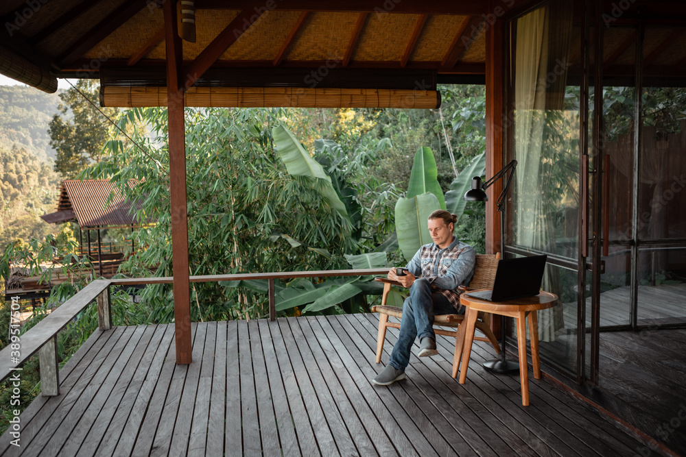 Rear view of male traveler blogger work remote on laptop computer while enjoying amazng nature moutains landscape view outdoors Rear view of male traveler blogger work remote on laptop computer while enjoying amazng nature moutains landscape view outdoors