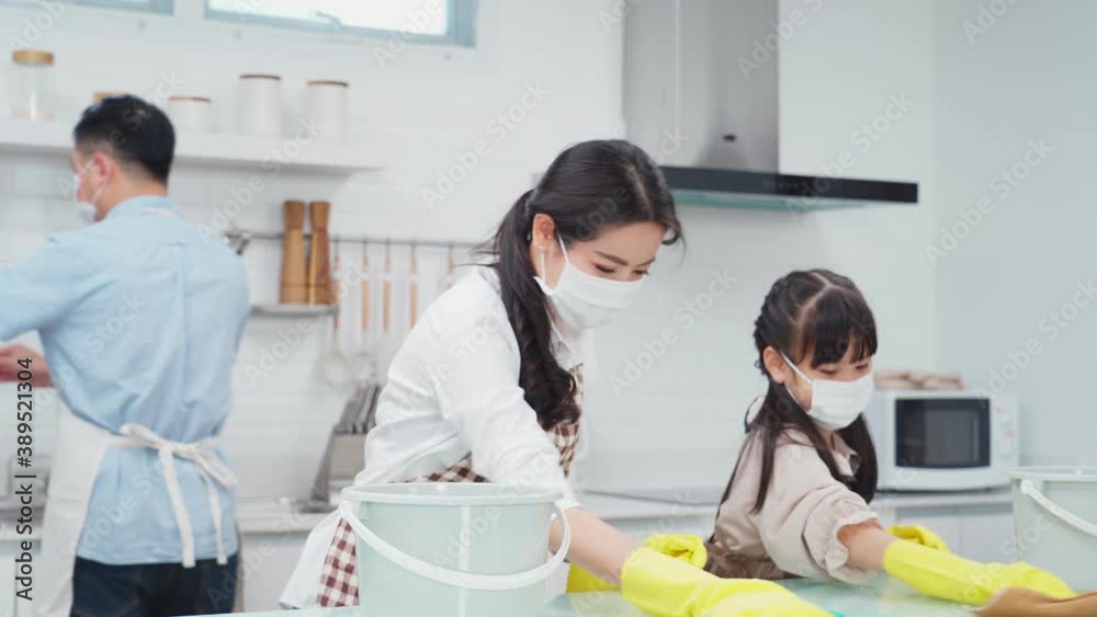 Asian mother and daughter wearing face mask, cleaning kitchen counter. Asian mother and daughter wearing face mask, cleaning kitchen counter.