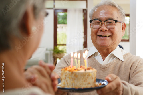 Asian senior man giving birthday cake celebration to senior woman with happy and enjoy, retirement family lifestyle at home