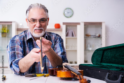 Obraz na plátně Senior male repairman repairing musical instruments at home