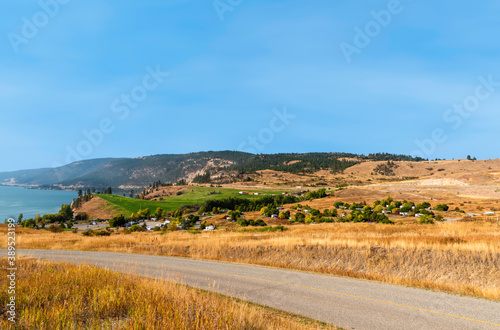 Asphalt road curving down to the river  yellow steppe grass along the edges of the road