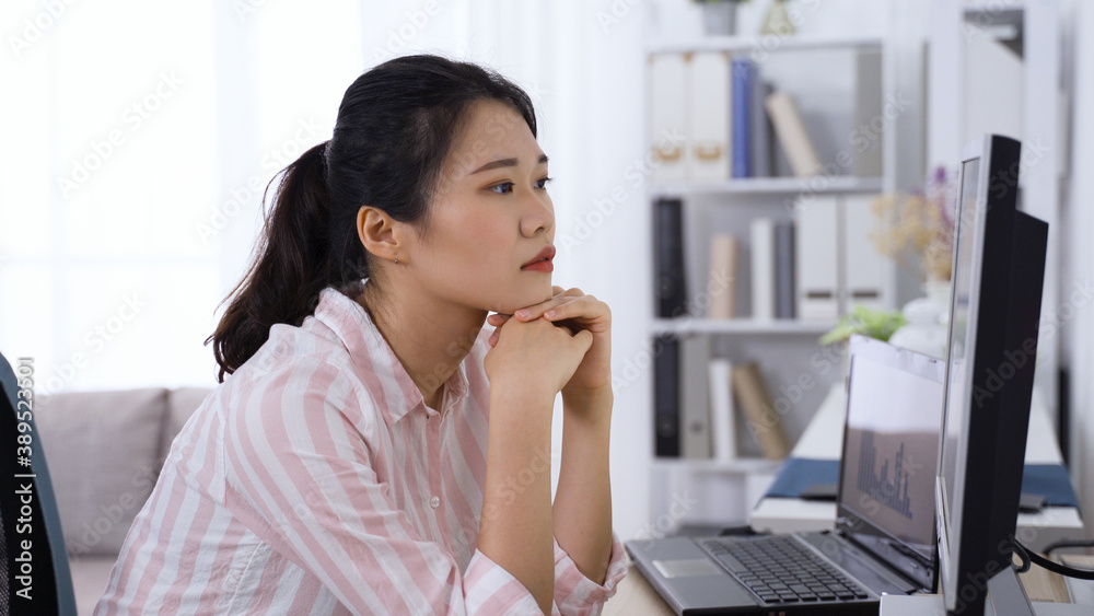 asian taiwanese lady employee propping head is having dry eyes while looking at data on computer in modern office. asian taiwanese lady employee propping head is having dry eyes while looking at data on computer in modern office.