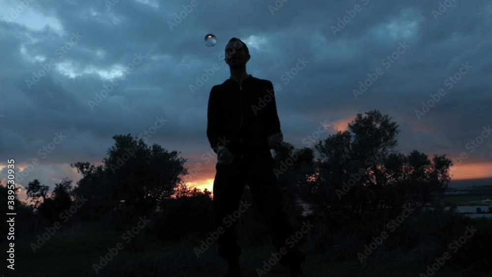 Juggling artist performing tricks with 3 transparent balls. Slow motion silhouette shot on a cloudy sunset background. Juggling artist performing tricks with 3 transparent balls. Slow motion silhouette shot on a cloudy sunset background.