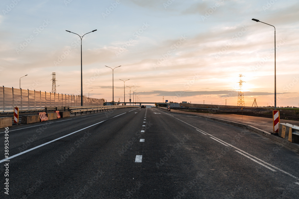 Newly built road with soundproof panels against the background of sunset