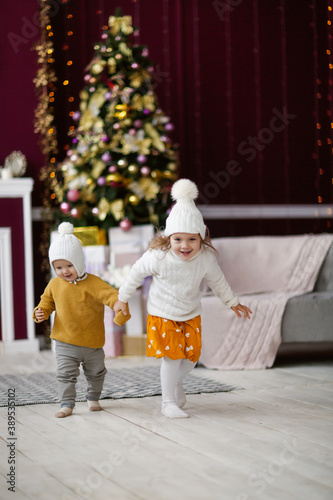 Obraz na plátně cozy New Year's children siblings in knitted hats and sweaters, gentle home phot
