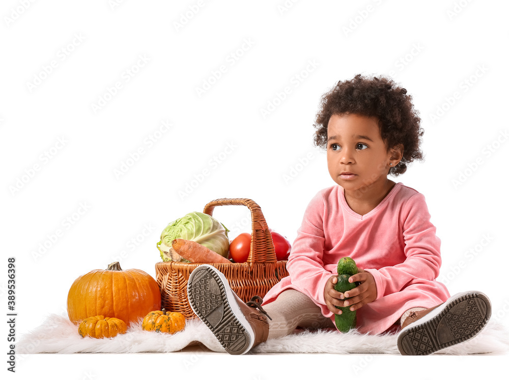 Fototapeta premium Cute African-American baby girl with harvest in basket on white background