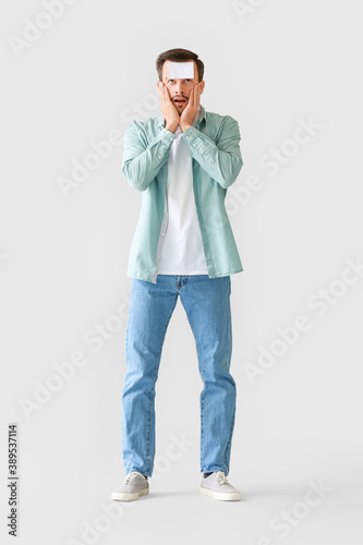 Confused man with blank note paper on his forehead against grey background