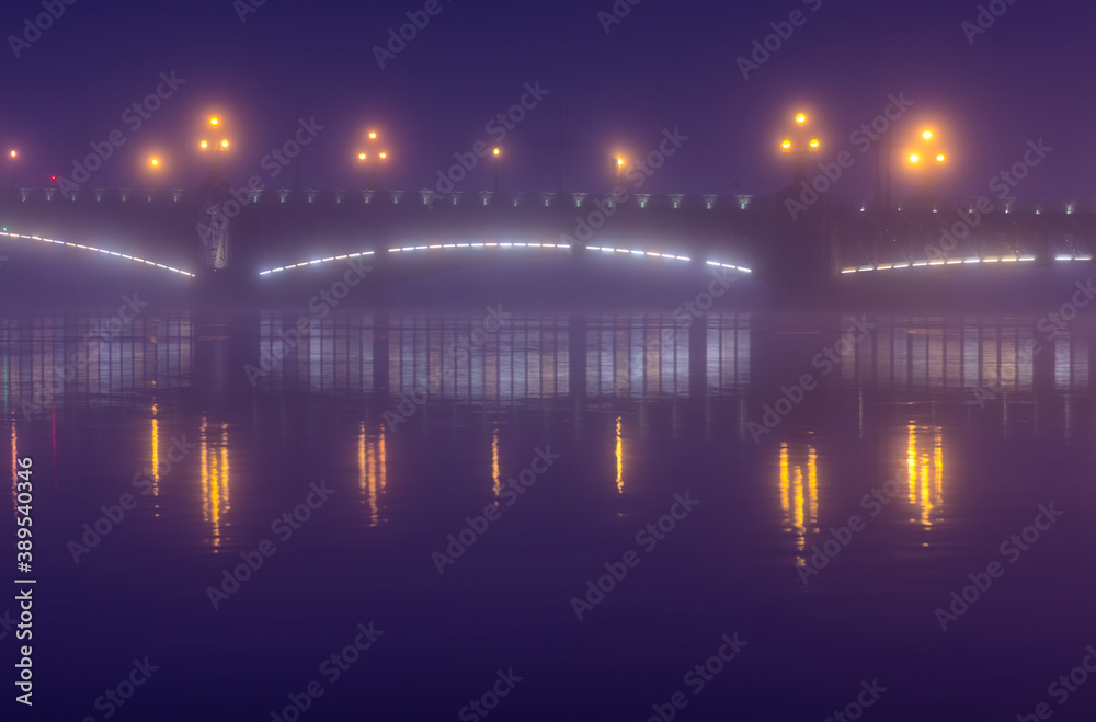 Foggy landscape of Trinity Bridge with glowing lanterns in the blue hour (Saint Petersburg, Russia)