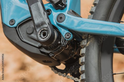 Details of electric mountain bicycle in blue color. Visible electric motor hidden in bottom bracket.