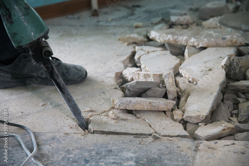 Foto A worker uses a jackhammer to remove a layer of old cement screed inside the rep