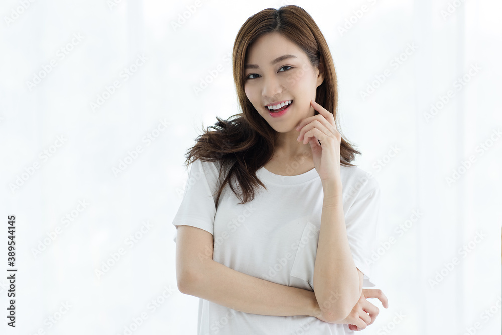 Portrait of beautiful cute young Asian woman smiling and looking to camera with a self-confident and graceful manner. She raises her hand to touch her chin with a friendly pose on white background Portrait of beautiful cute young Asian woman smiling and looking to camera with a self-confident and graceful manner. She raises her hand to touch her chin with a friendly pose on white background