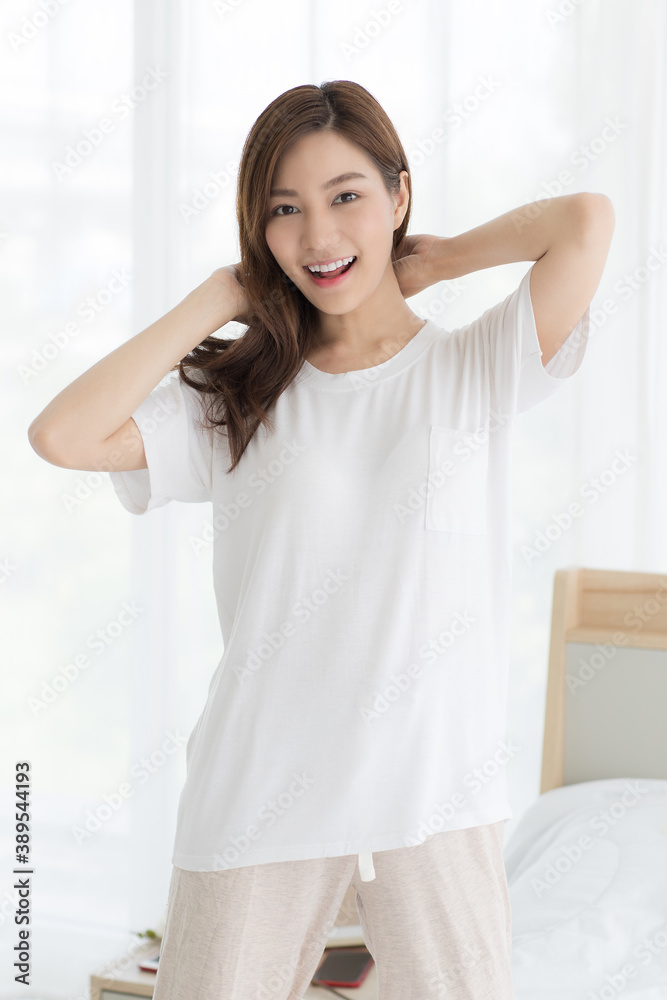 Lovely portrait of cute beautiful young Asian woman posing with cheerful and friendly smile show tidy and nice teeth on bed in bedroom with natural light white background. Lovely portrait of cute beautiful young Asian woman posing with cheerful and friendly smile show tidy and nice teeth on bed in bedroom with natural light white background.