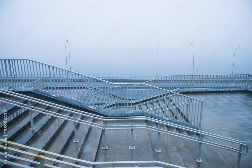 Fototapeta premium Embankment and city road near the river in heavy fog