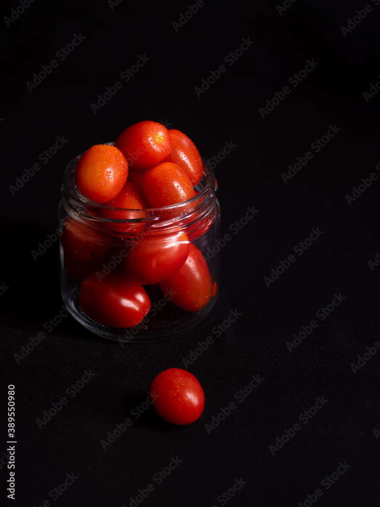 low key photo of cherry tomatoes in a glass jar isolated on black background low key photo of cherry tomatoes in a glass jar isolated on black background