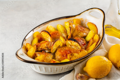 Baked lemon garlic chicken and butter with potato. Light grey background. photo