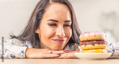 Foto Woman passionately looking forward to eat a pile of doughnuts