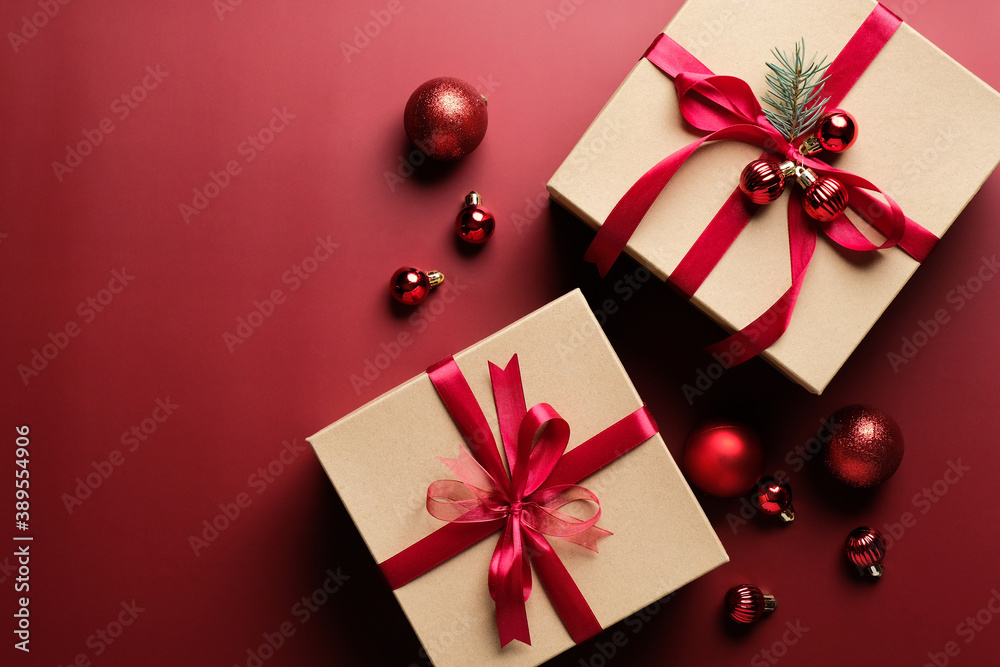 Kraft paper gift boxes decorated red ribbon and balls on marsala red background. Flat lay, top view. Christmas gifts, New Year present concept. Kraft paper gift boxes decorated red ribbon and balls on marsala red background. Flat lay, top view. Christmas gifts, New Year present concept.