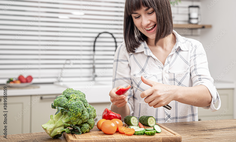 Young beautiful woman preparing fresh vegetable salad. Healthy food and diet concept.