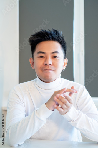 Job promotion. Successful career. Corporate congratulation. Portrait of confident satisfied asian man in white looking at camera applauding at light workspace.