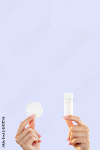 Makeup remover. Facial skincare. Cleansing product. Wellness hygiene. Minimal presentation of mockup bottle with foam cotton pad in female hands isolated on pastel blue copy space background.