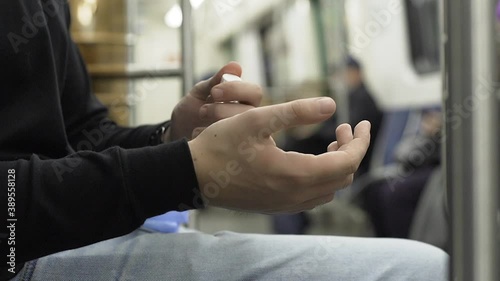 Young man takes off his medical gloves and use antiseptic in publuc transport during pandemic covid-19 coronavirus quarantine. Keep yourself and others safety. photo