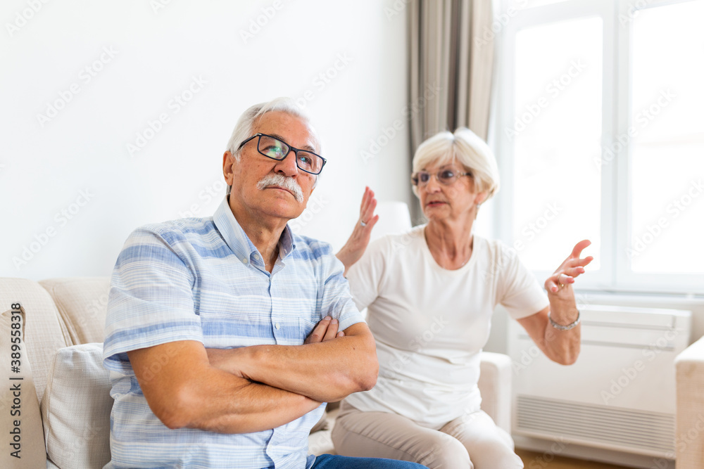 Angry elderly woman arguing with her husband. Senior couple having difficulty in marriage. Old couple sitting on the sofa at home Angry elderly woman arguing with her husband. Senior couple having difficulty in marriage. Old couple sitting on the sofa at home